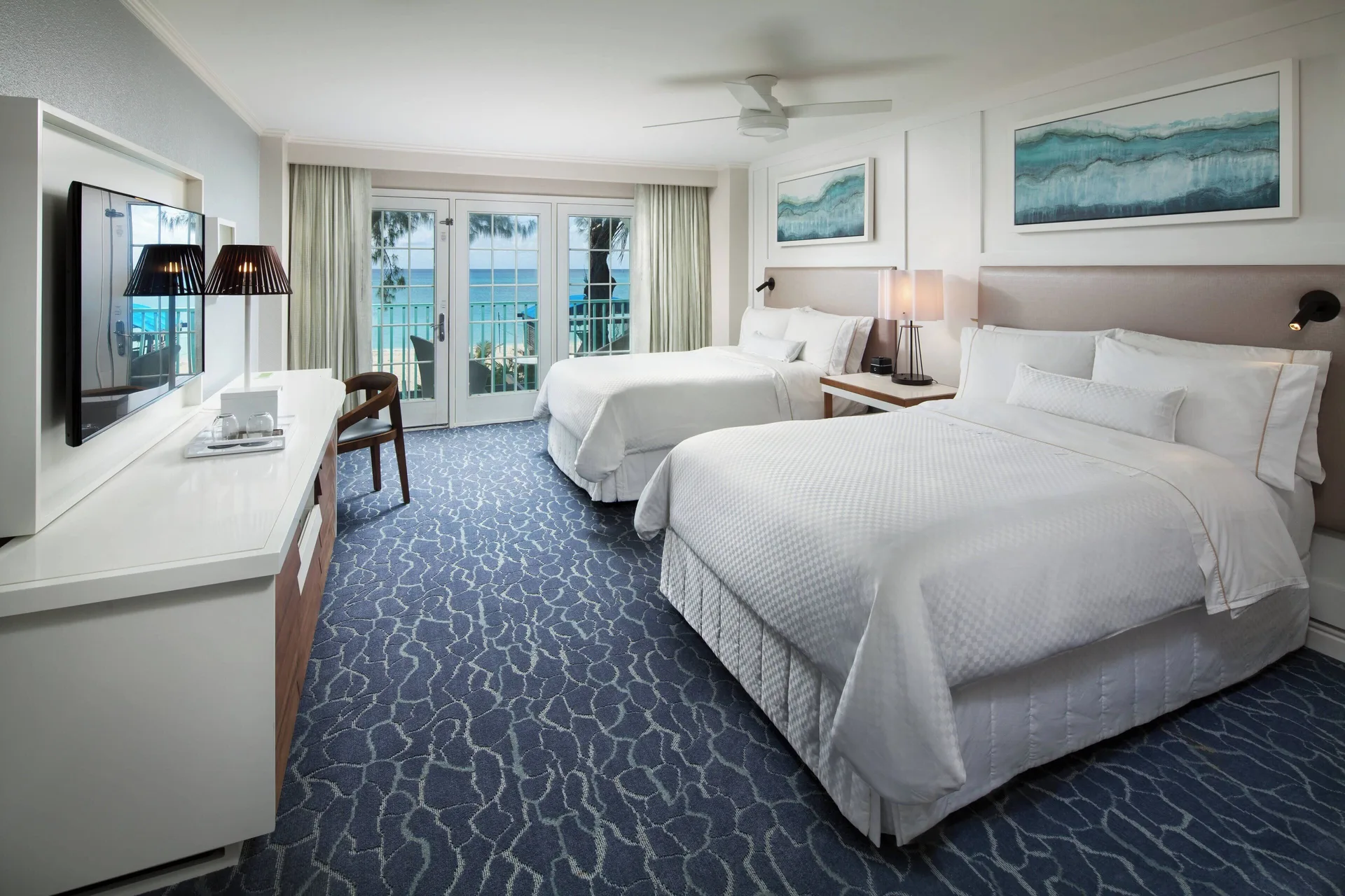 Two queen beds, desk, and balcony doors in a room at The Westin Grand Cayman Seven Mile Beach Resort & Spa.