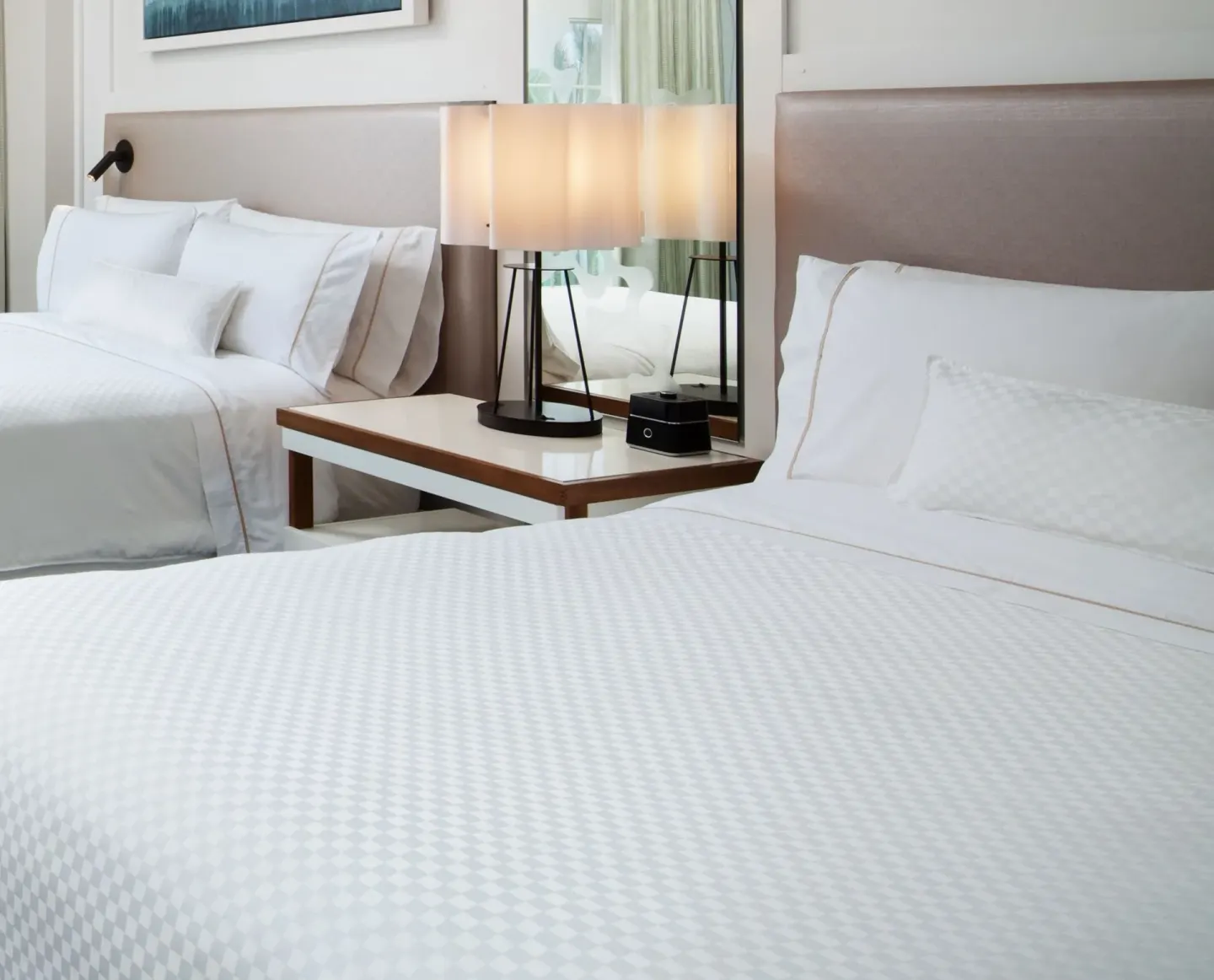 Close-up of two guest room beds and bedside lamp at The Westin Grand Cayman Seven Mile Beach Resort & Spa.