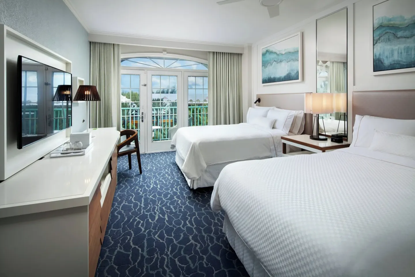 Two-bed guest room with balcony doors and media console at The Westin Grand Cayman Seven Mile Beach Resort & Spa.