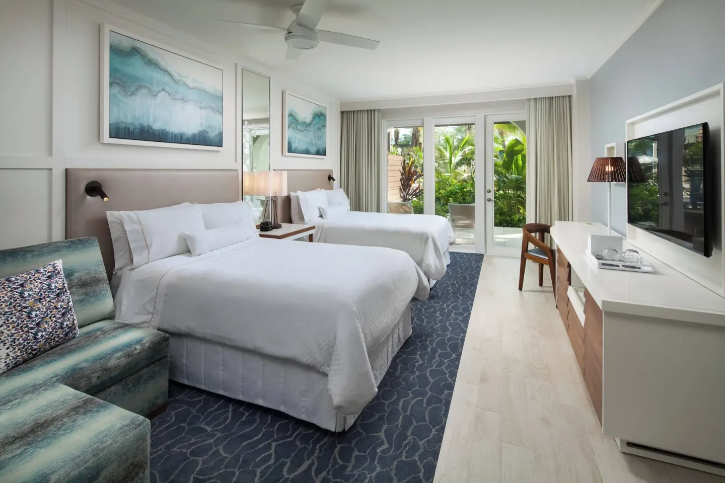 Two-bed guest room with seating and garden-facing doors at The Westin Grand Cayman Seven Mile Beach Resort & Spa.