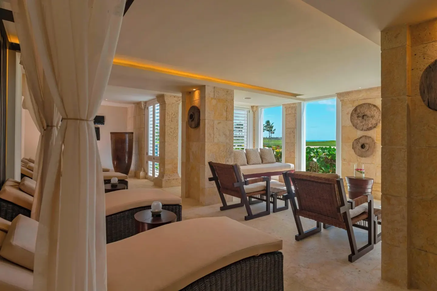 Covered beachfront lounge with daybeds and wicker chairs at The Westin Puntacana Resort.