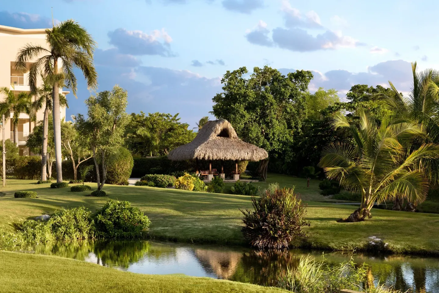 Garden pond, palms, and thatched pavilion at The Westin Puntacana Resort.