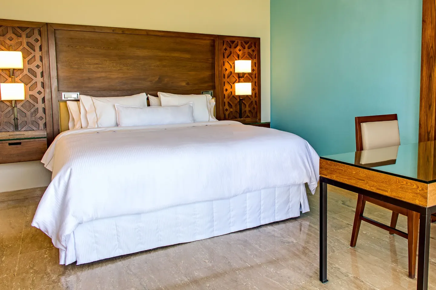 Guest room at The Westin Puntacana Resort with a king bed, wood headboard and glass-top desk.