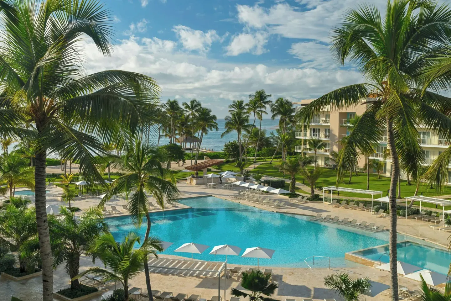 Main pool, palm trees, and ocean beyond at The Westin Puntacana Resort.