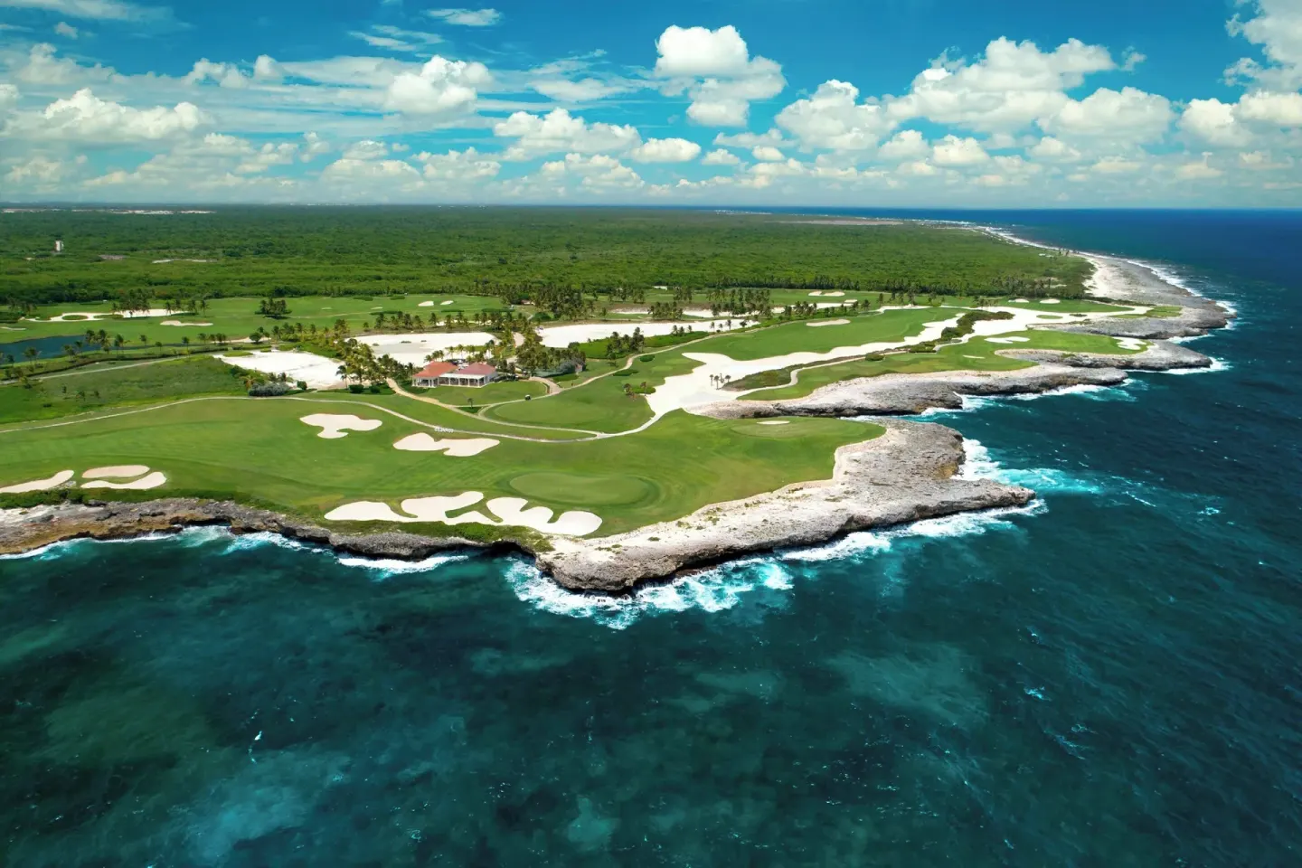 An aerial view shows oceanfront golf greens and rocky coastline at The Westin Puntacana Resort.