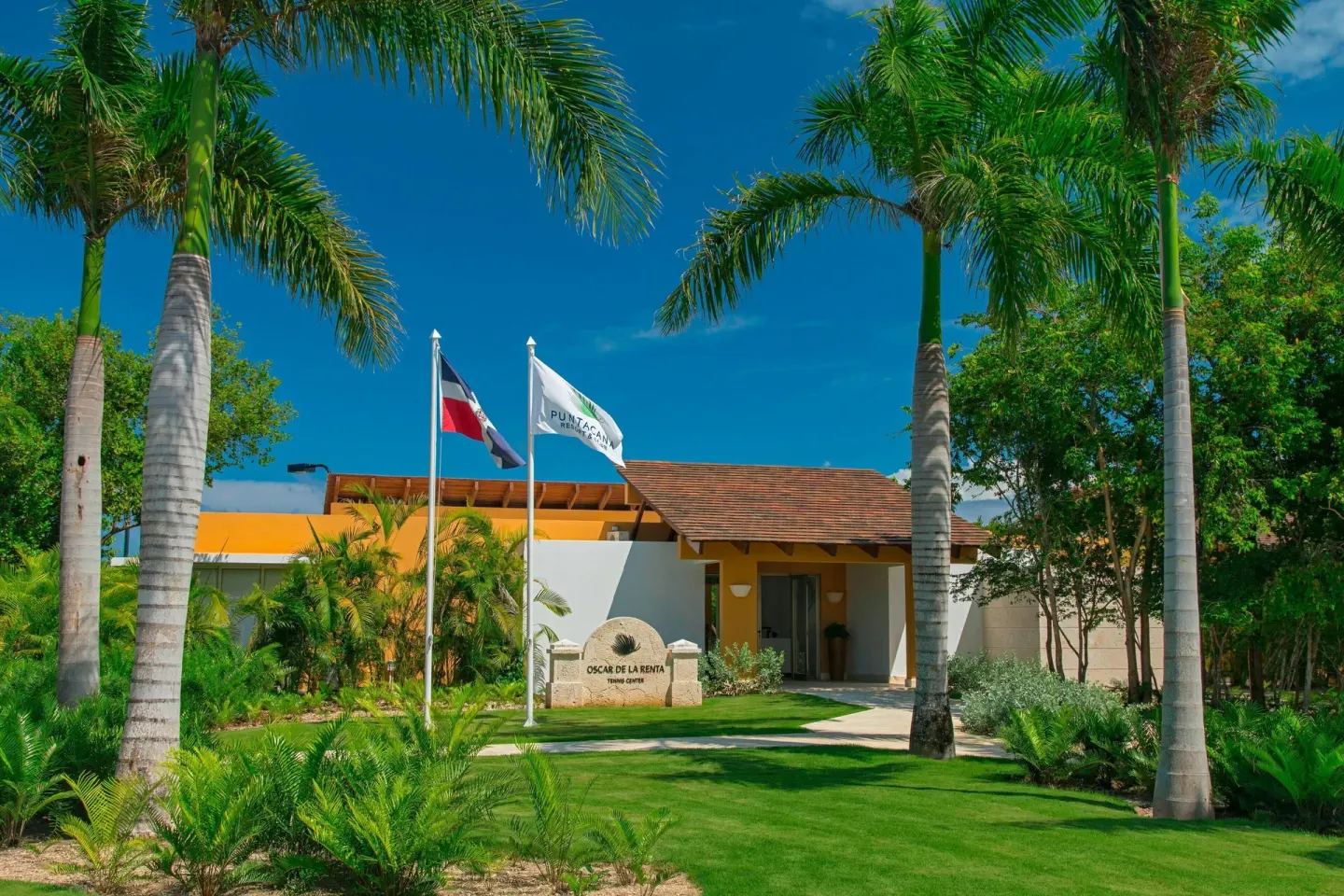 Palm-lined entrance with flags and landscaping at The Westin Puntacana Resort.