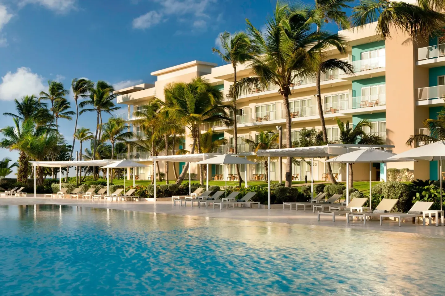 Pool, loungers, palms, and guest balconies at The Westin Puntacana Resort.