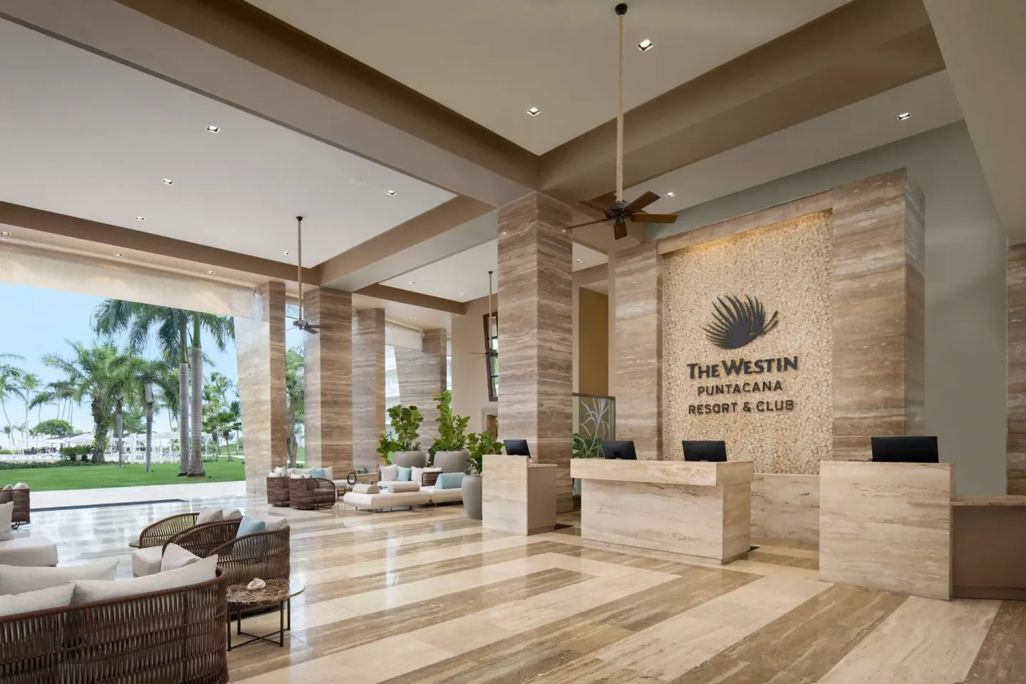 Reception area at The Westin Puntacana Resort with stone desks, logo wall and open garden view.
