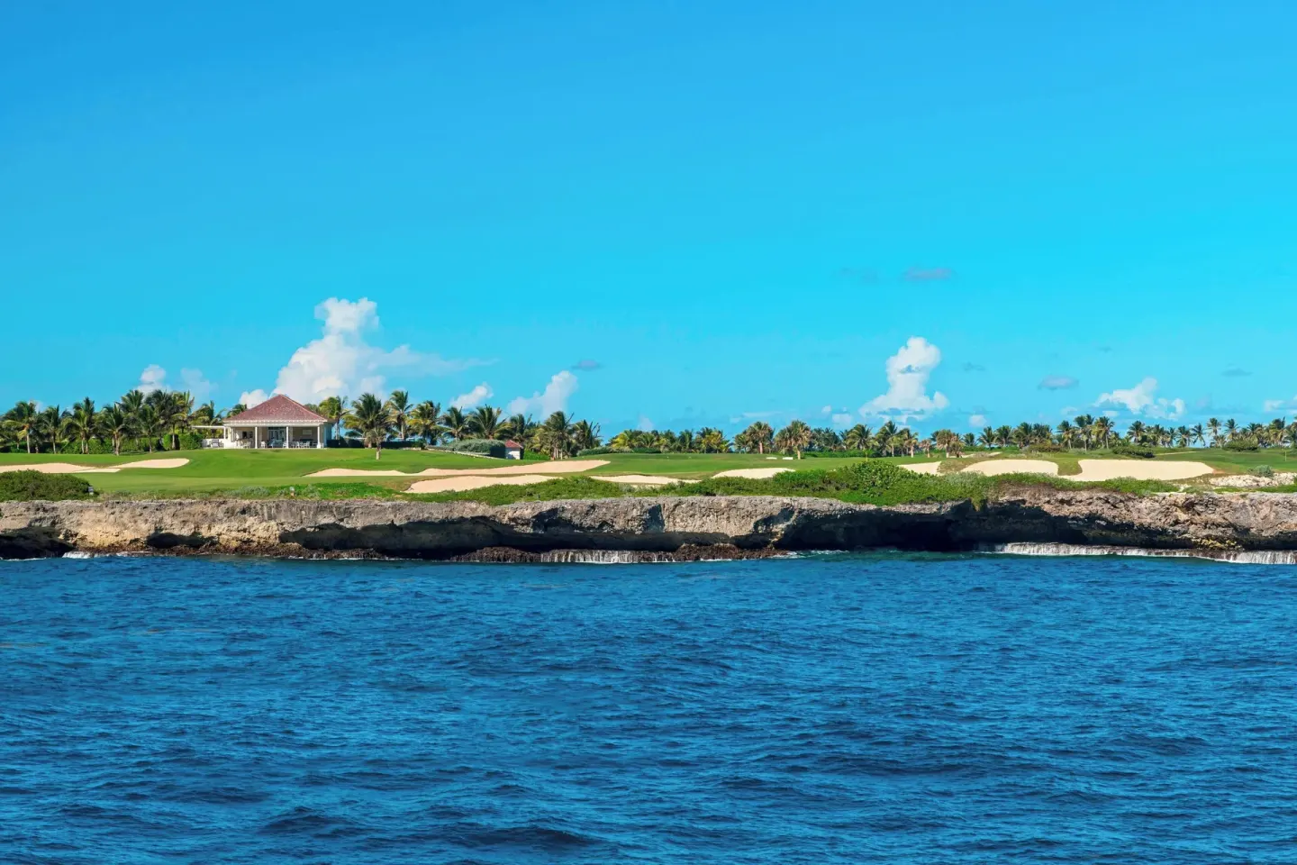 A seaside golf course sits above blue water and rocky shoreline at The Westin Puntacana Resort.