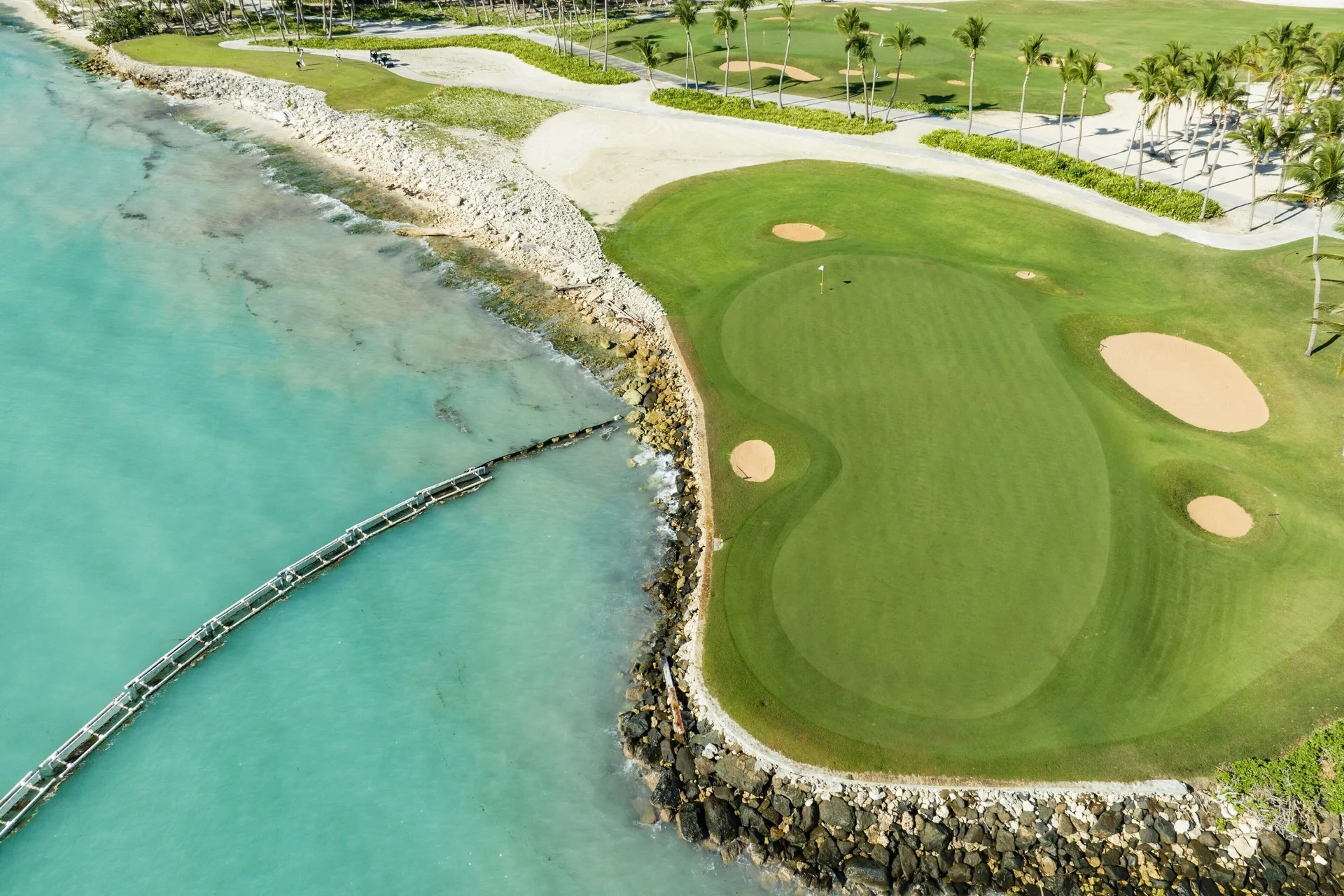 Aerial view of a seaside golf green and curved walkway at The Westin Puntacana Resort.