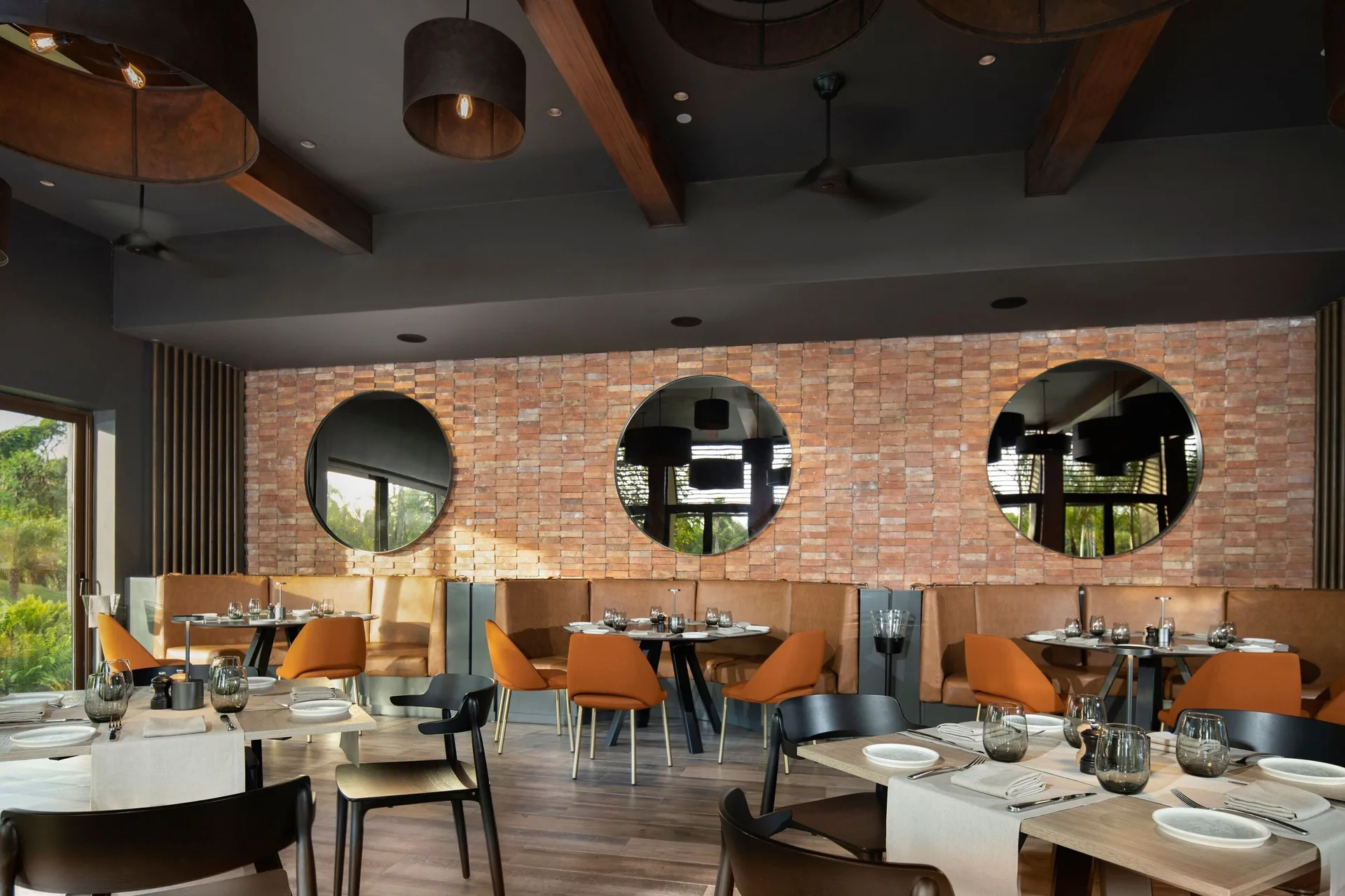 Restaurant dining room with brick wall and round mirrors at The Westin Puntacana Resort.