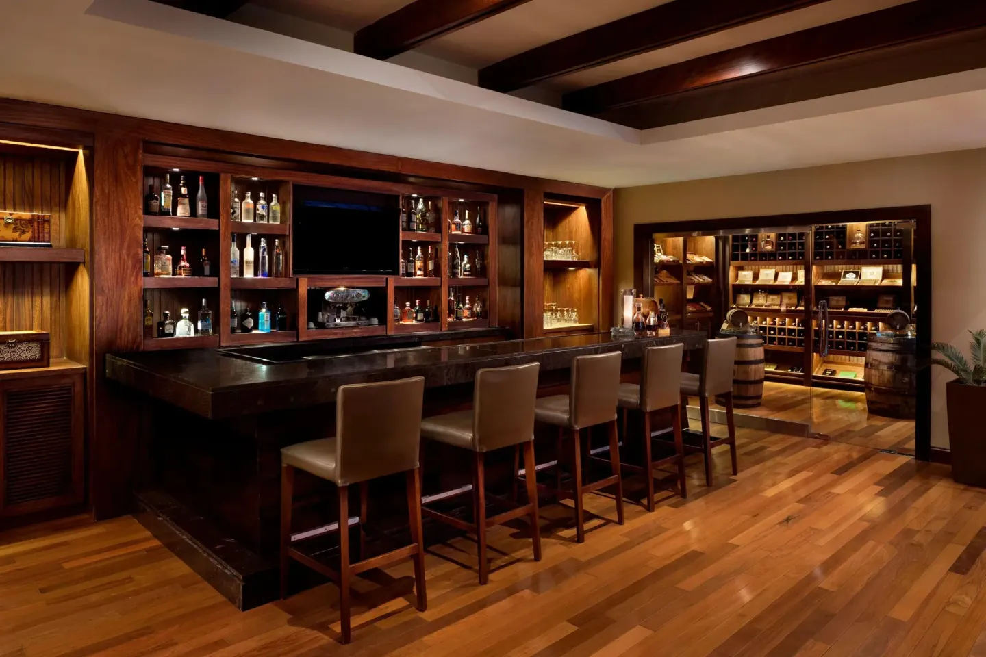 Wood-paneled cigar lounge bar with leather stools at The Westin Puntacana Resort.