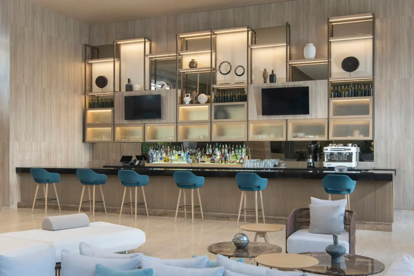 Lobby bar at The Westin Puntacana Resort with teal stools, backlit shelves and lounge seating.