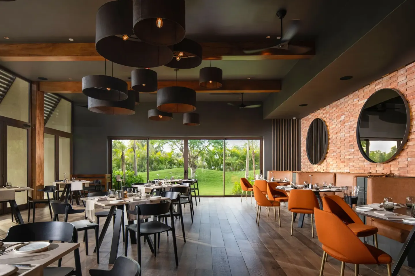 Modern restaurant dining room with brick wall and garden views at The Westin Puntacana Resort.