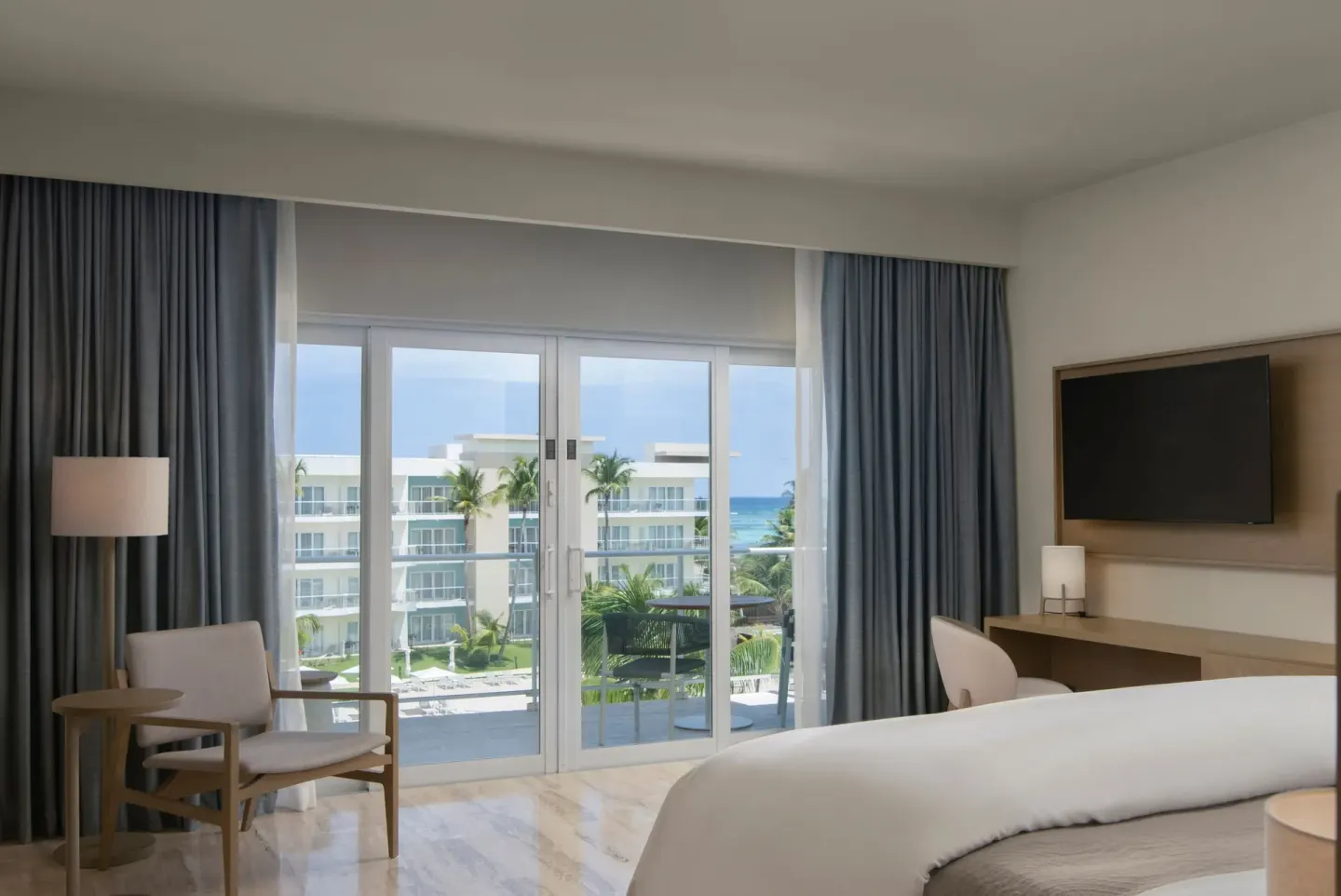 Premium Room with bed, balcony doors, ocean view, chair, desk, and TV at The Westin Puntacana Resort.