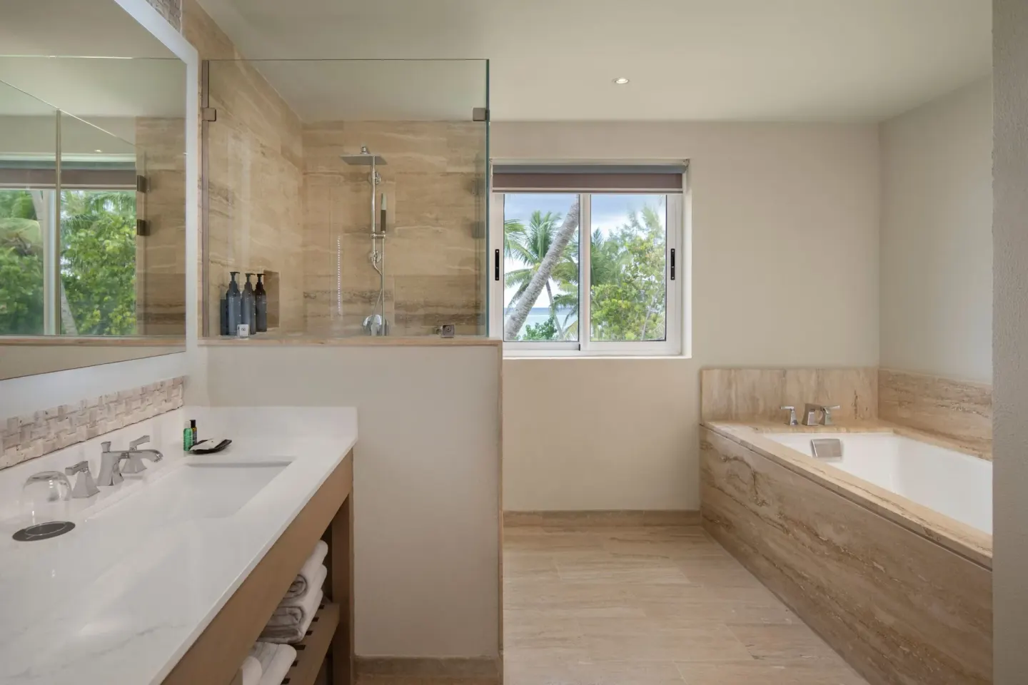 Suite bathroom at The Westin Puntacana Resort with soaking tub, glass shower, vanity, and palm-view window.