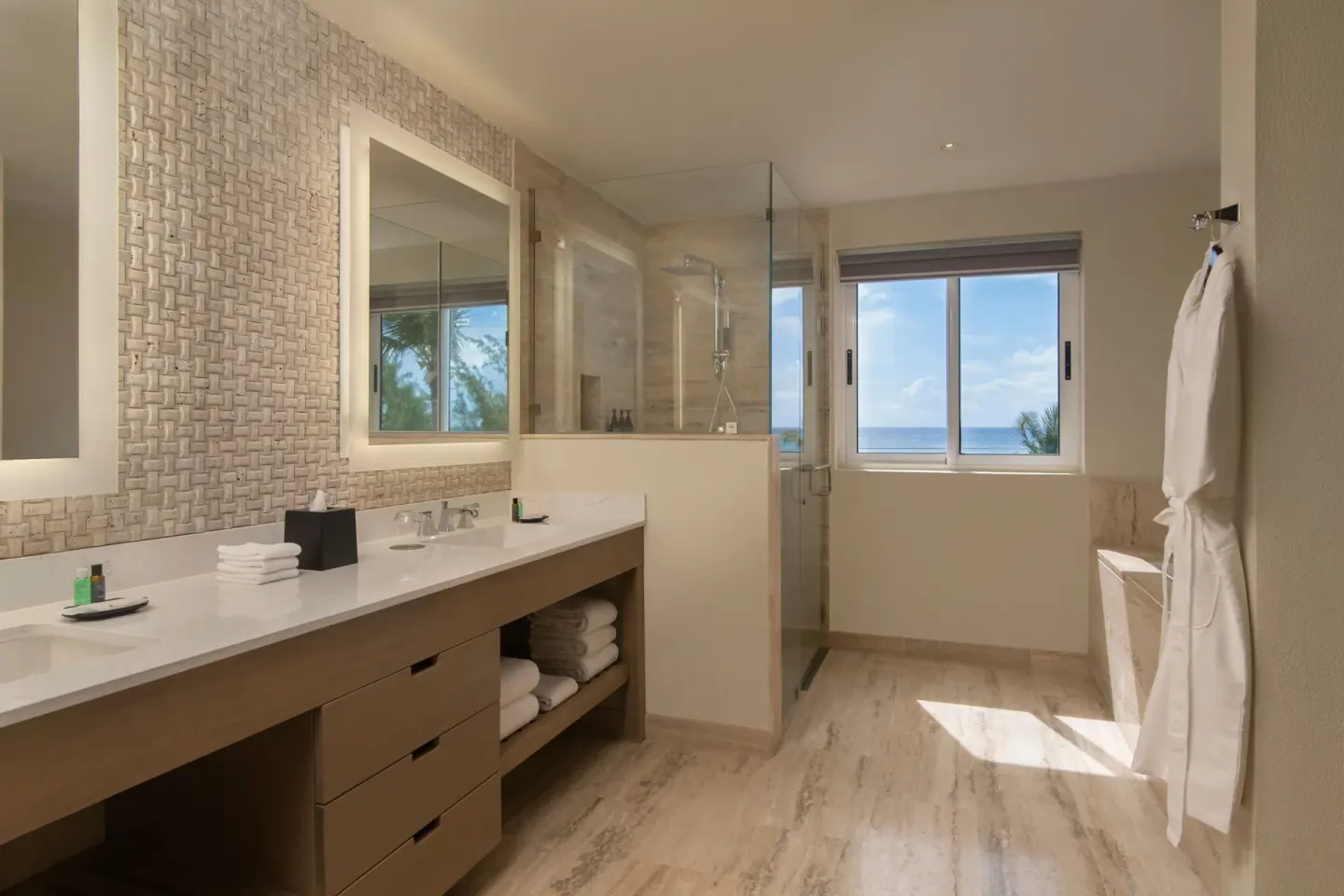 Suite bathroom at The Westin Puntacana Resort with long vanity, glass shower, robe, and ocean-view window.