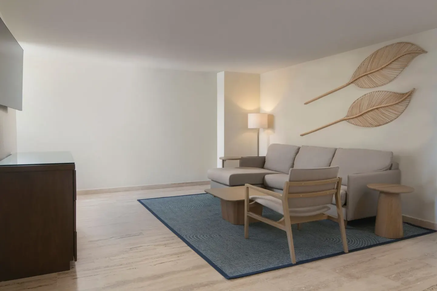 Suite sitting room at The Westin Puntacana Resort with sectional sofa, rug, lamp, and leaf wall art.