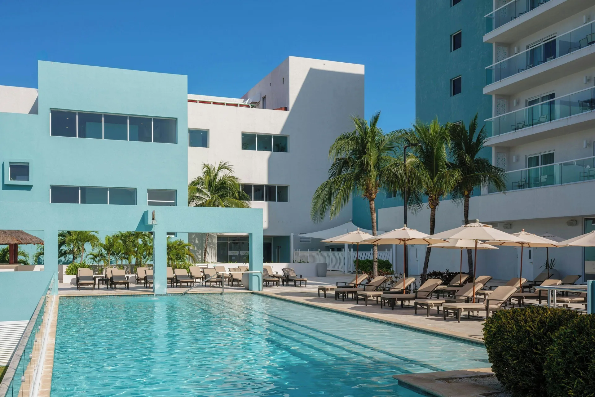 Modern pool area with loungers and palm trees at The Westin Resort & Spa, Cancun.