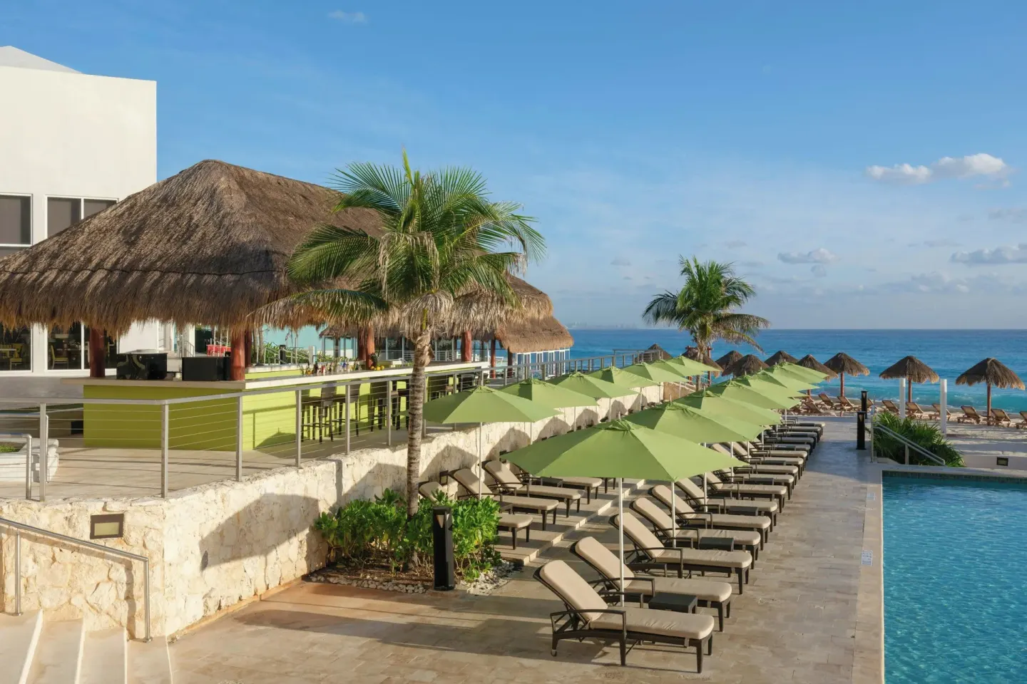 Pool loungers, green umbrellas and oceanfront palapas at The Westin Resort & Spa, Cancun.