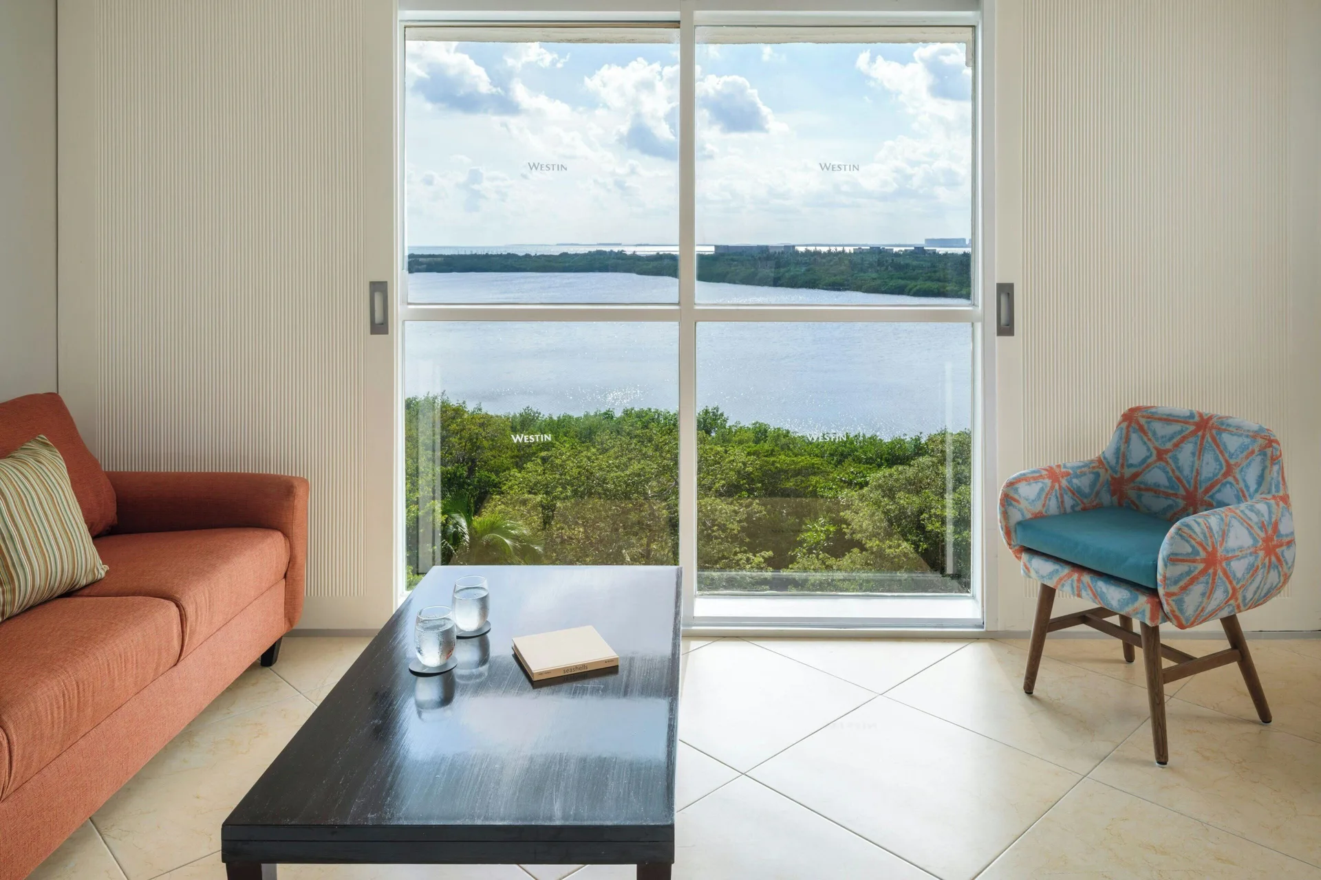 Junior Suite lounge corner with sofa, chair, coffee table, and lagoon view at The Westin Resort & Spa, Cancun.