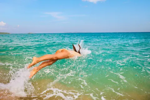Swimmer diving into turquoise water near The Westin St. Thomas Beach Resort & Spa.