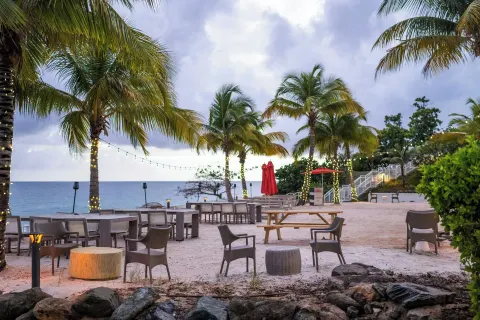 Oceanfront seating and picnic tables on sand at The Westin St. Thomas Beach Resort & Spa.