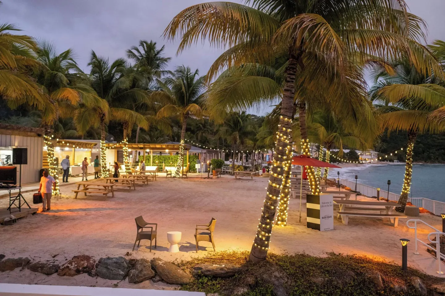 Sandy beachfront gathering area with lit palms at The Westin St. Thomas Beach Resort & Spa.