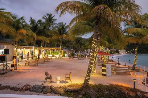 Sandy beachfront gathering area with lit palms at The Westin St. Thomas Beach Resort & Spa.