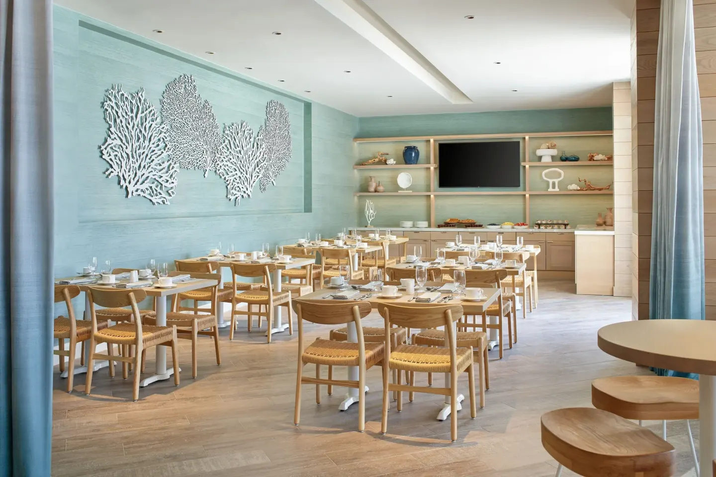 Dining room with coral wall art and set tables at The Westin St. Thomas Beach Resort & Spa.