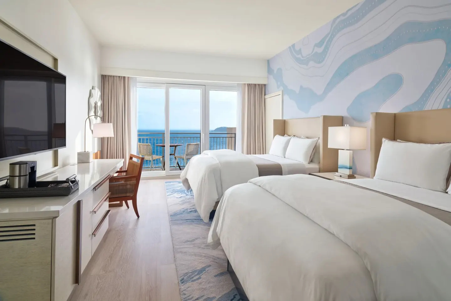 Two-bed partial ocean view room at The Westin St. Thomas Beach Resort & Spa with balcony seating and ocean beyond.