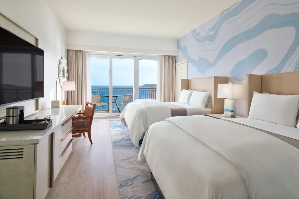 Two-bed partial ocean view room at The Westin St. Thomas Beach Resort & Spa with balcony seating and ocean beyond.