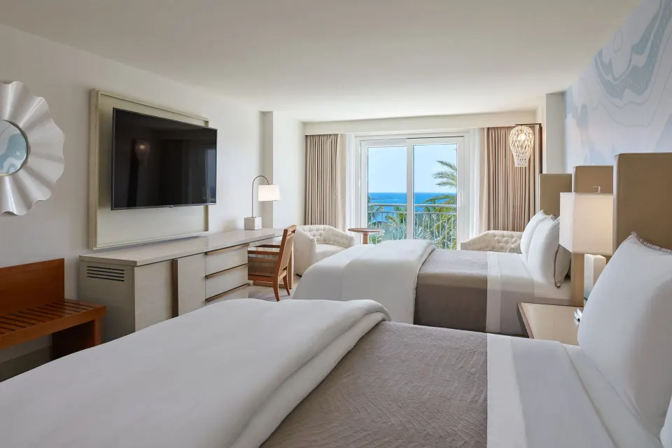 Two-bed partial ocean view room at The Westin St. Thomas Beach Resort & Spa with balcony doors and TV.