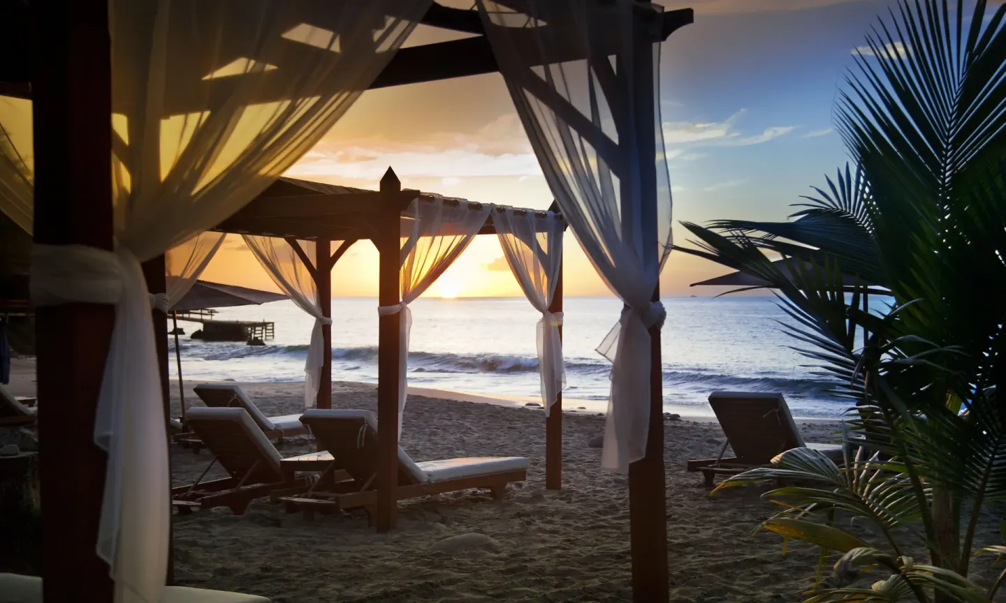 Ocean sunset framed by beach cabanas at Ti Kaye Resort & Spa.