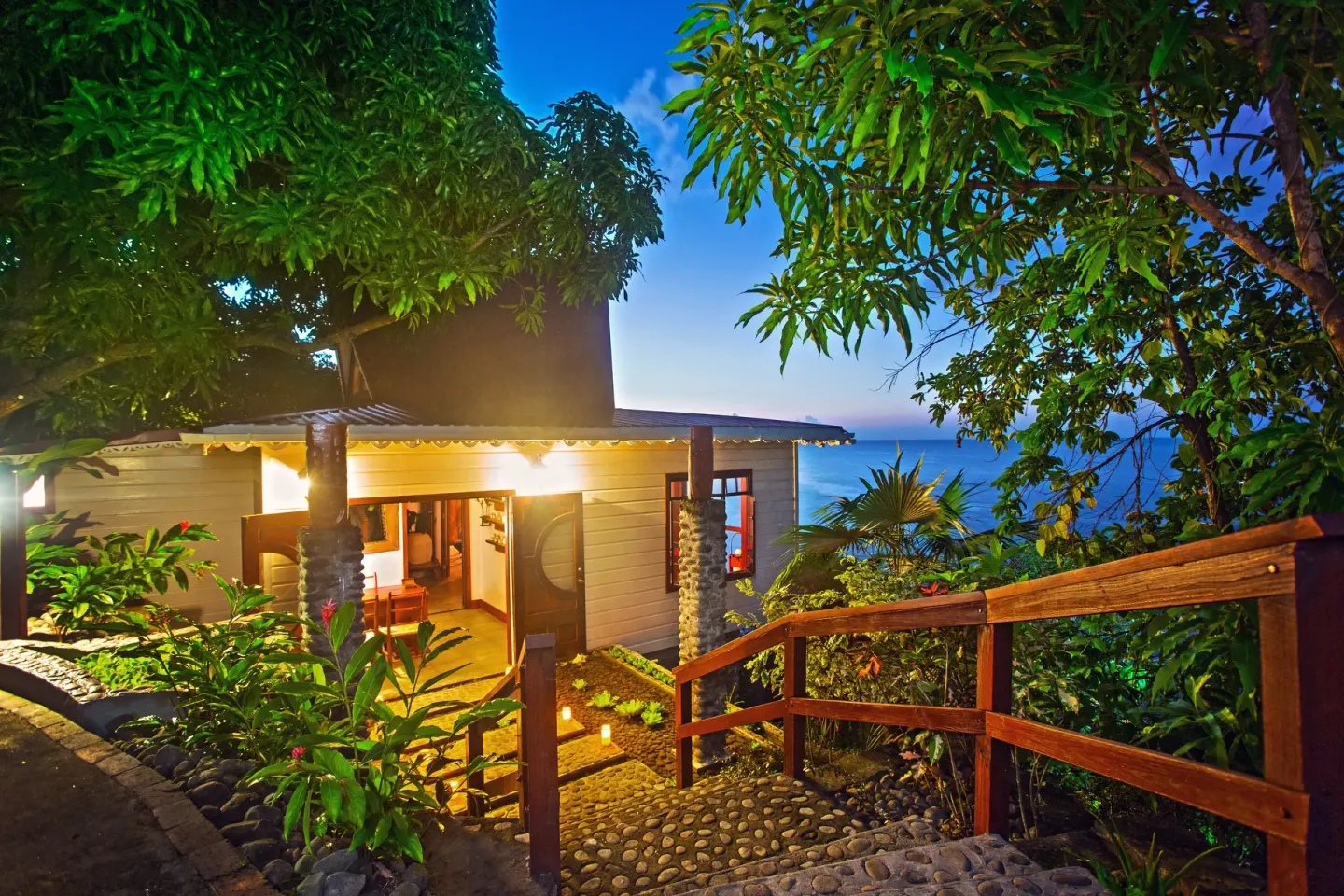 Garden walkway and cottage exterior at dusk at Ti Kaye Resort & Spa.