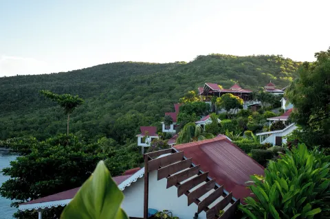 Hillside cottages and red roofs among greenery at Ti Kaye Resort & Spa.