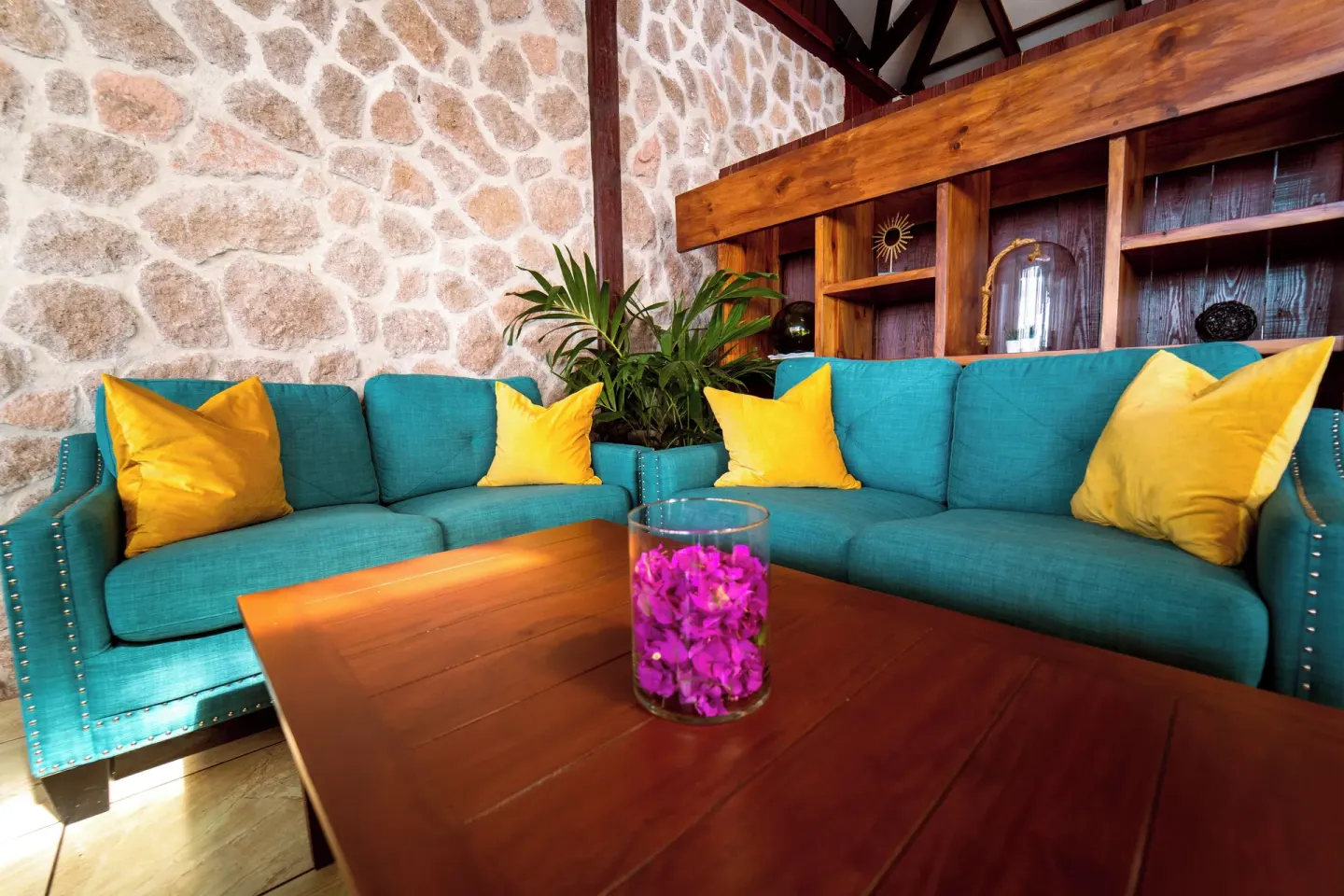 Turquoise sofas with yellow pillows furnish a stone-walled lounge at Ti Kaye Resort & Spa.