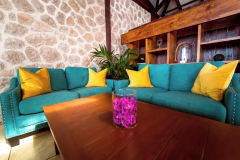 Turquoise sofas with yellow pillows furnish a stone-walled lounge at Ti Kaye Resort & Spa.