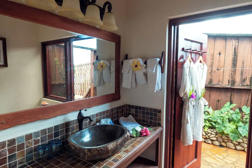 Ocean View Cottage with Pool bathroom at Ti Kaye Resort & Spa with stone basin and open garden door.