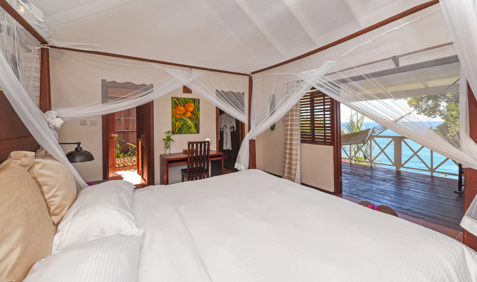 Ocean View Cottage king bed with mosquito netting and sea-facing veranda at Ti Kaye Resort & Spa.