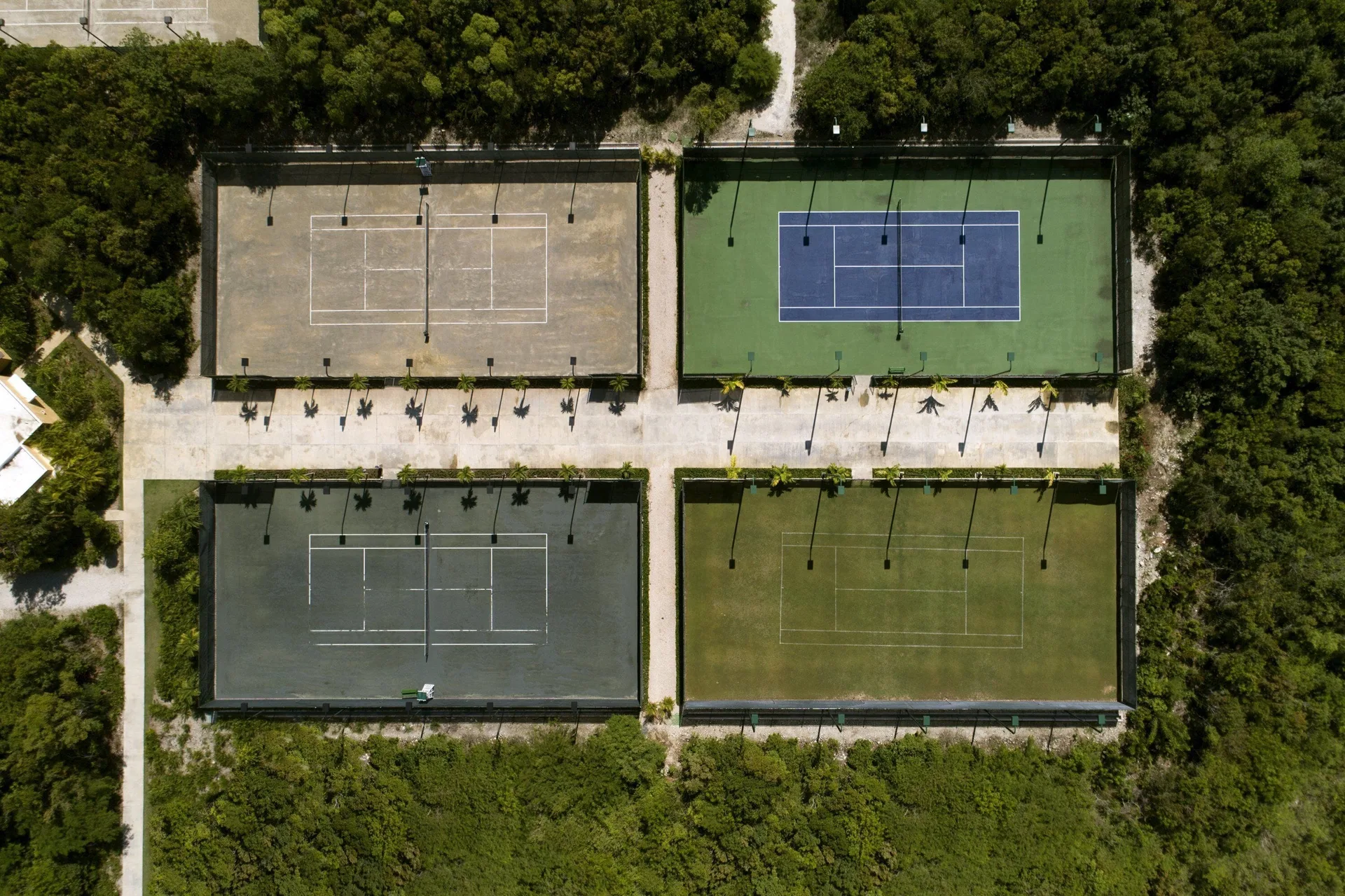 Aerial view of four tennis courts surrounded by greenery at Tortuga Bay Hotel.