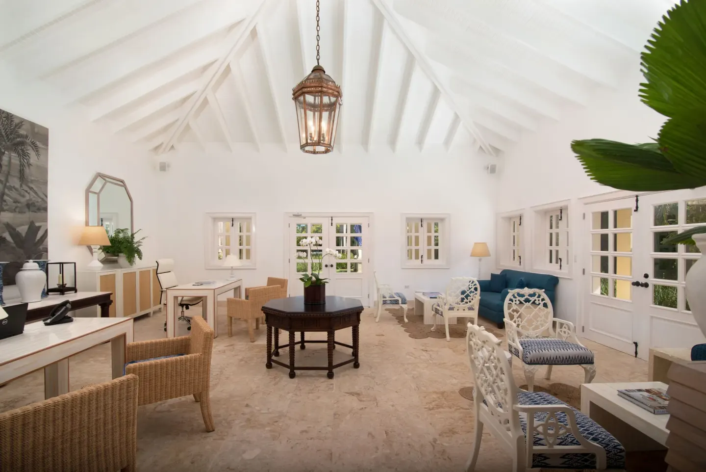 Bright lounge with vaulted white ceiling, desks, seating, and French doors at Tortuga Bay Hotel.