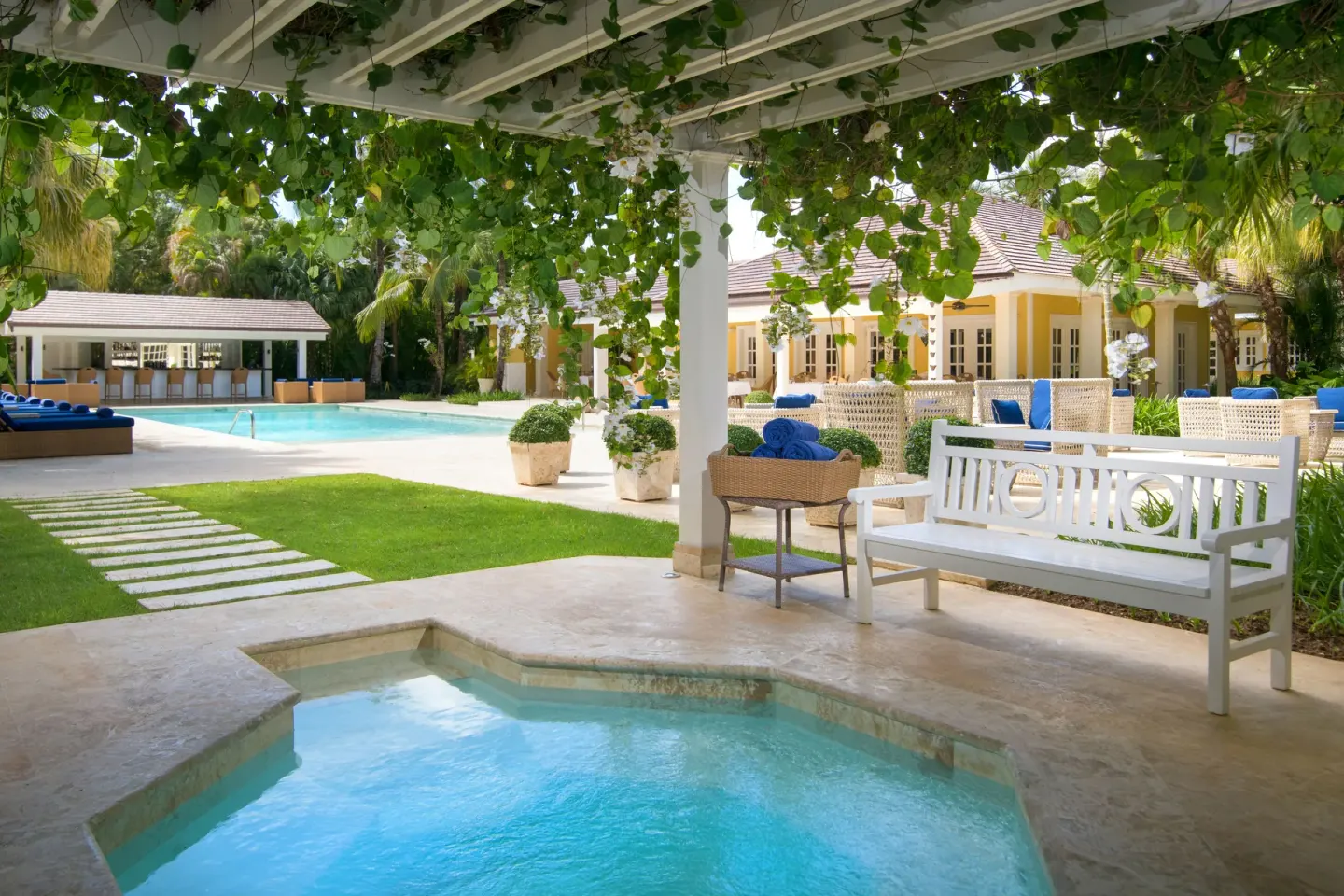 Covered patio with small plunge pool and white bench at Tortuga Bay Hotel.