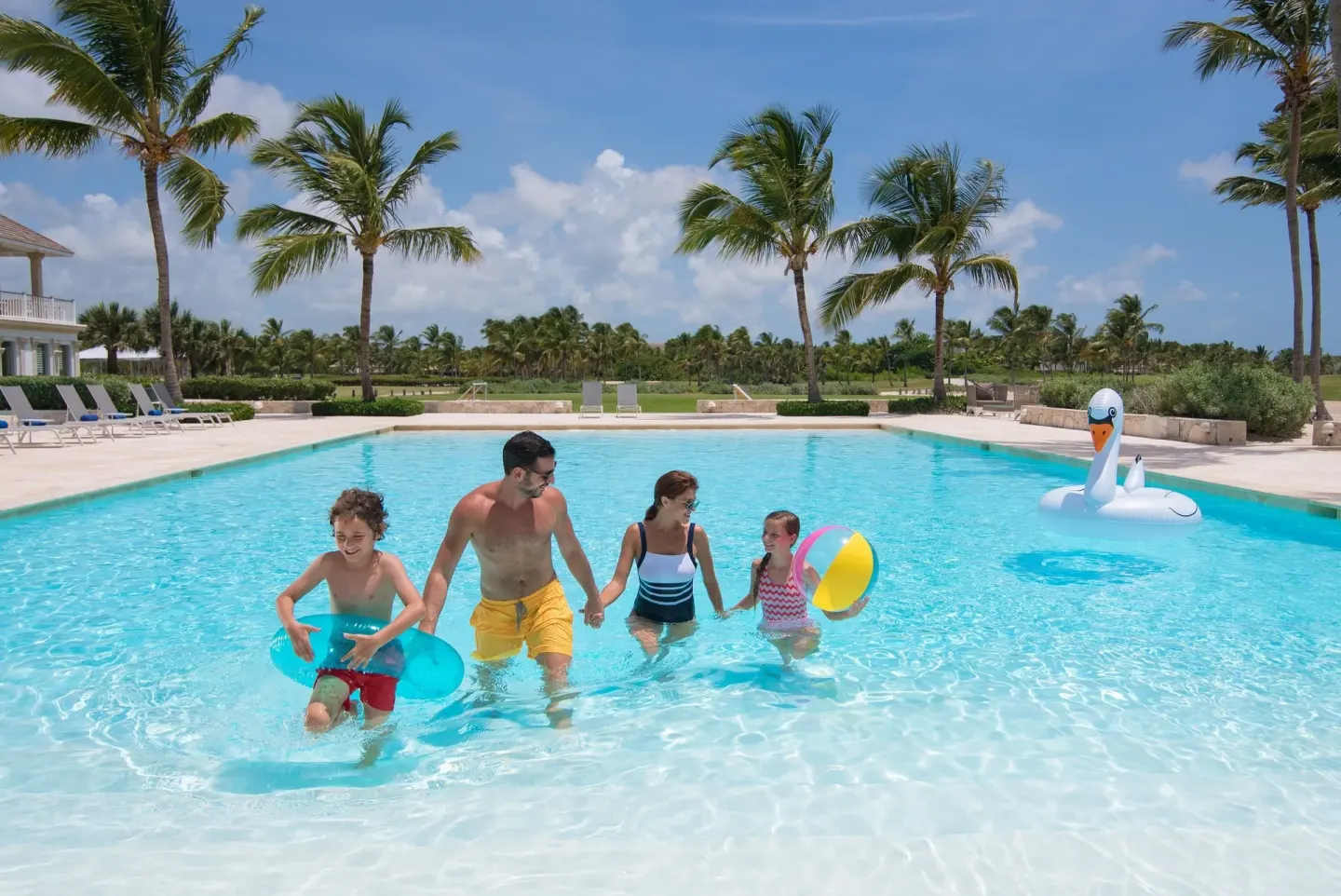 A family plays with floats in a palm-lined pool at Tortuga Bay Hotel.