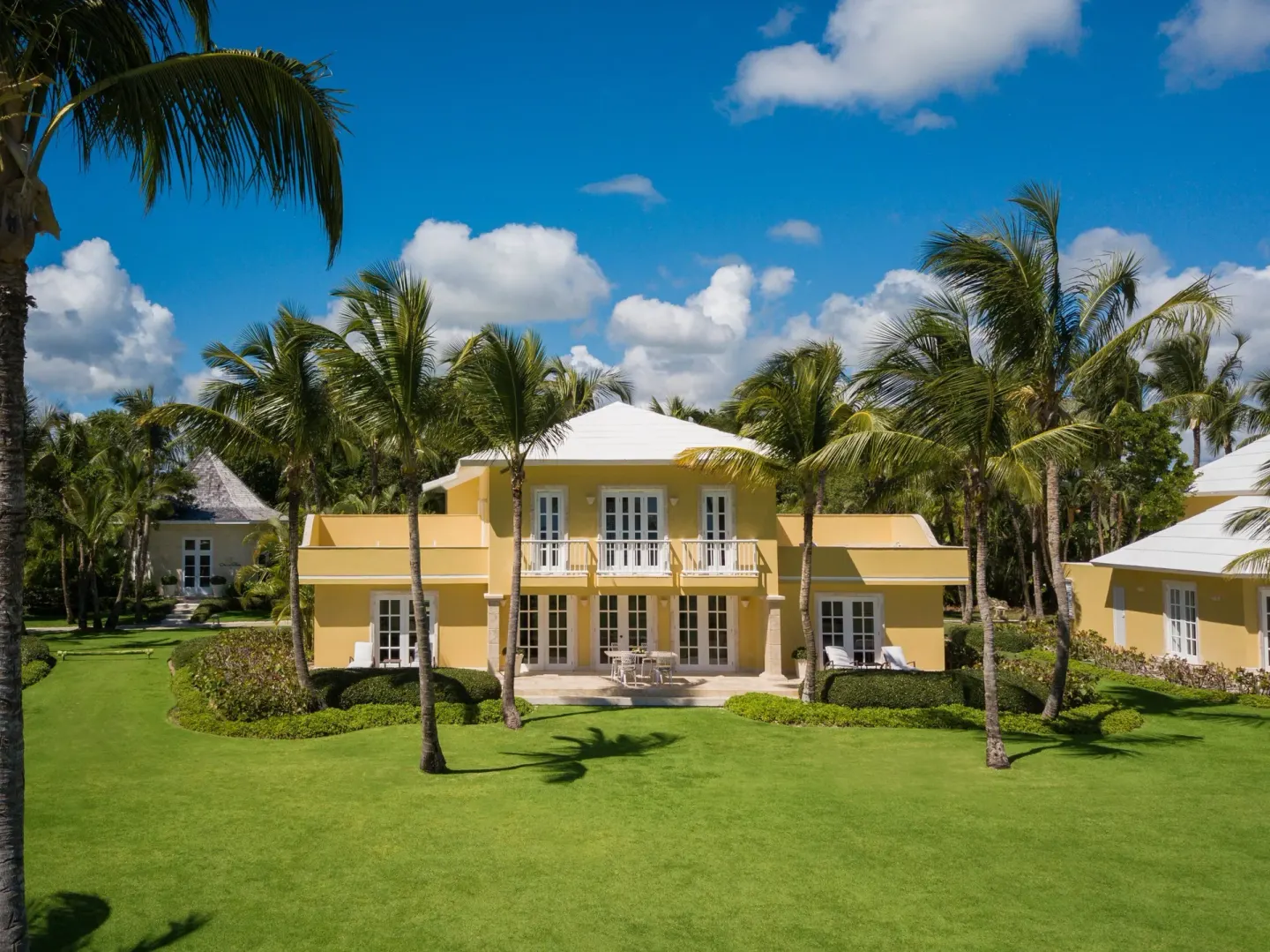 A yellow villa surrounded by palms and green lawn at Tortuga Bay Hotel.