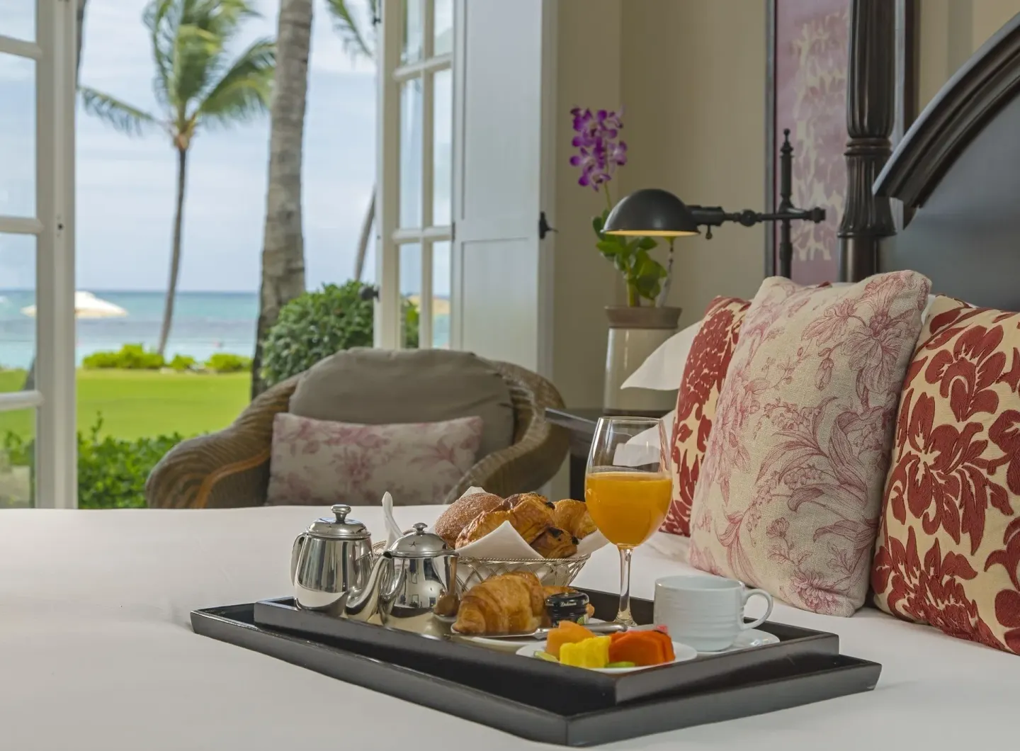 Breakfast tray on a bed at Tortuga Bay Hotel beside open doors to the sea.