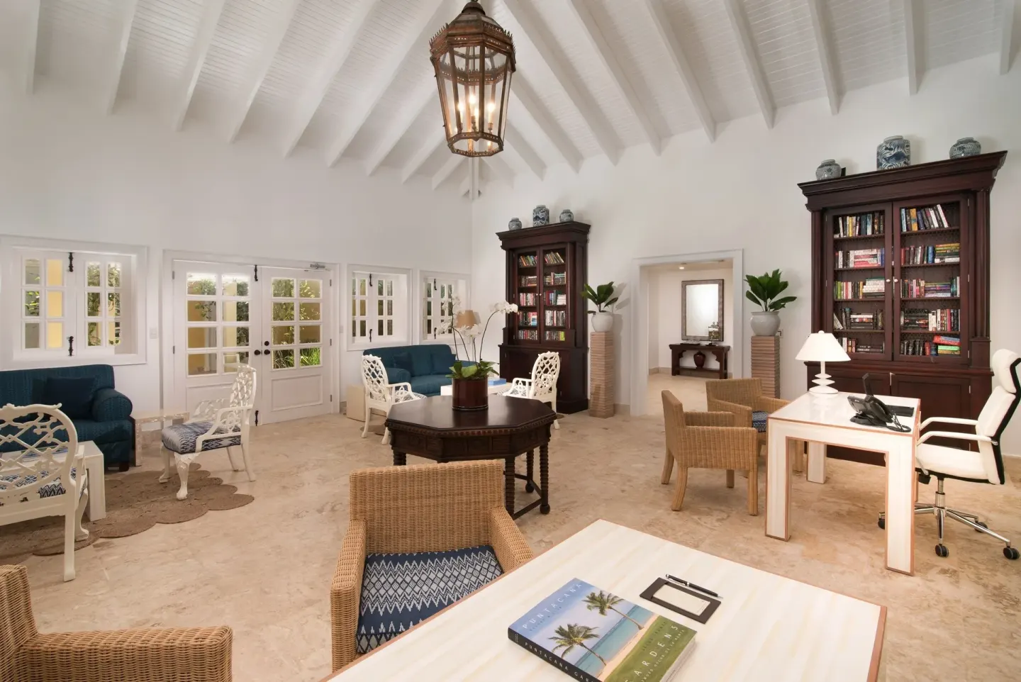 Resort lounge with bookcases, desks, blue sofas, and white vaulted ceiling at Tortuga Bay Hotel.