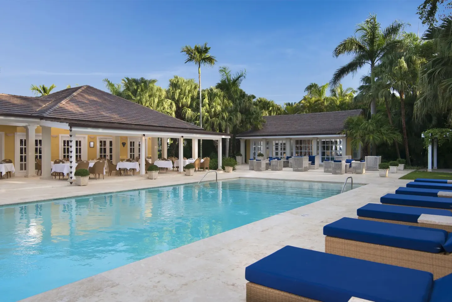 Main pool with blue loungers and open-air dining areas at Tortuga Bay Hotel.