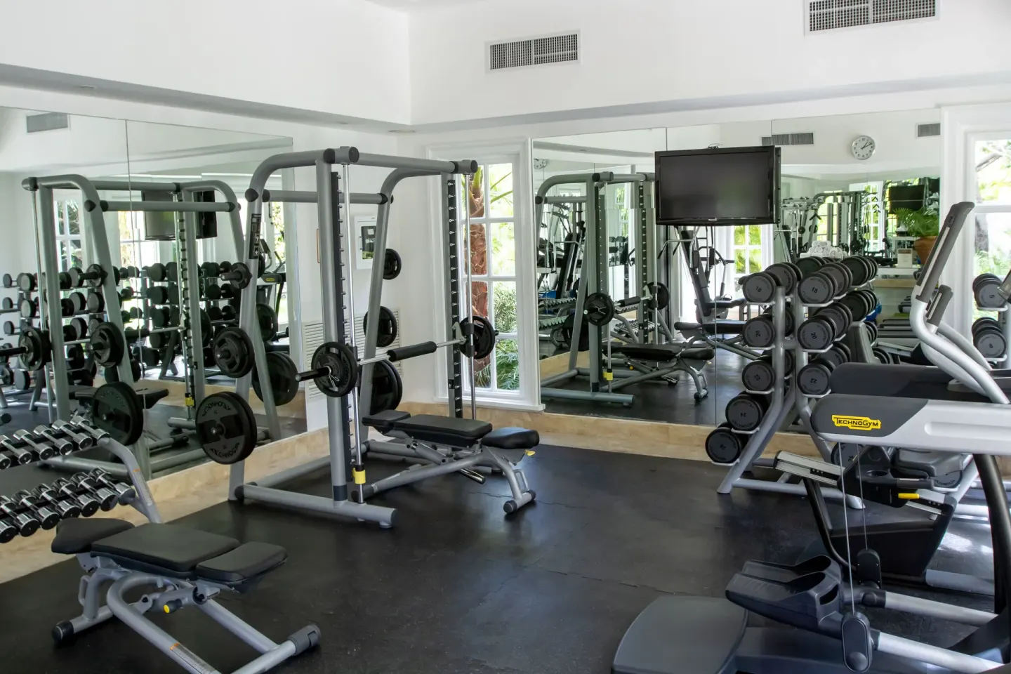 Gym with mirrors, weights, benches, and cardio equipment at Tortuga Bay Hotel.