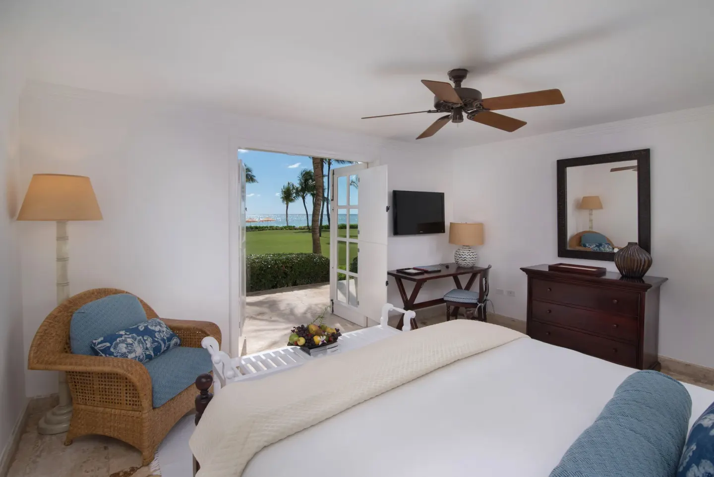 King bedroom at Tortuga Bay Hotel with open doors to lawn, palms, and ocean.